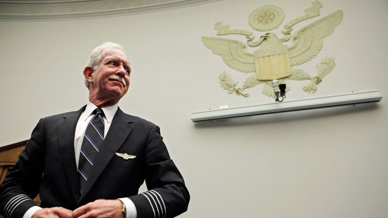 US Airways Captain Chesley "Sully" Sullenberger stands, buttoning his suit jacket, as he prepares to testify before a House Judiciary subcommittee on Capitol Hill on December 16, 2009.