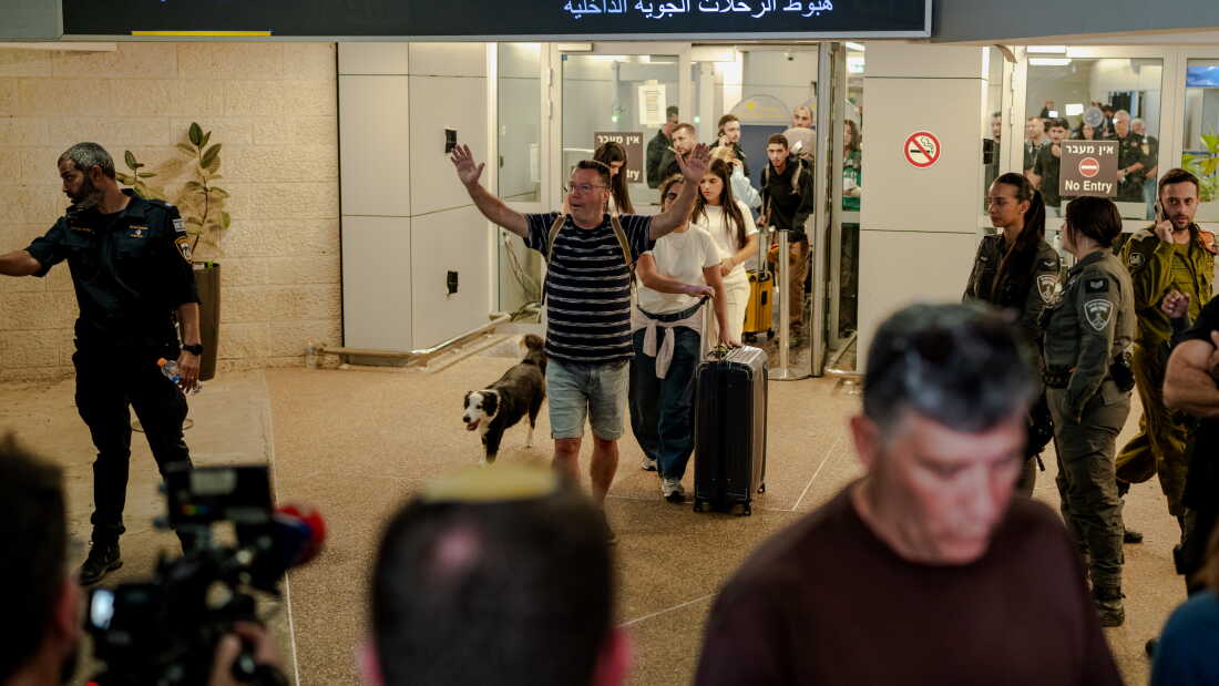 TZAFRIA, ISRAEL - SEPTEMBER 30: A passenger raises his arms in relief as he walks through the domestic arrivals doors with his dog and luggage at Ben Gurion Airport on September 30, 2026 in Tzafria, Israel. A flydubai flight from Dubai to Tel Aviv was diverted to Saudi Arabia after a violent altercation in the cockpit.
