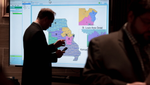 Onlookers gather around a large screen displaying Missouri congressional maps during an extraordinary legislative session Monday, Sept. 8, 2025, at the Capitol in Jefferson City, Mo.