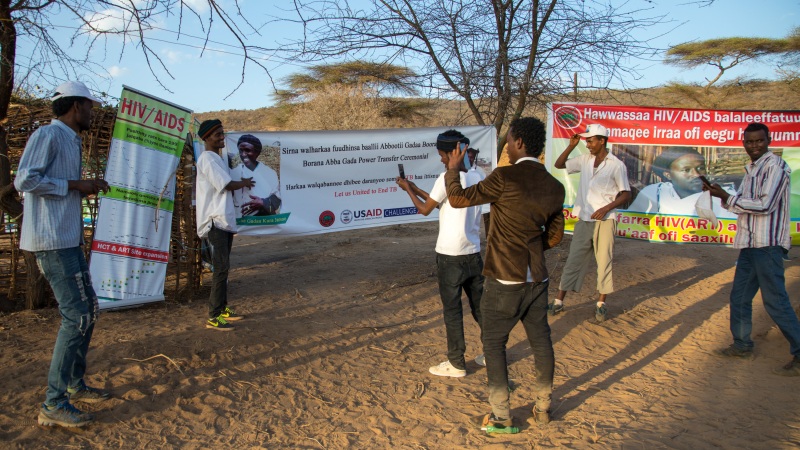 YABELO, ETHIOPIA - MARCH 06: Young men taking pictures in front of HIV billboards during the Gada system ceremony in Borana tribe, Oromia, Yabelo, Ethiopia on March 6, 2017 in Yabelo, Ethiopia. 