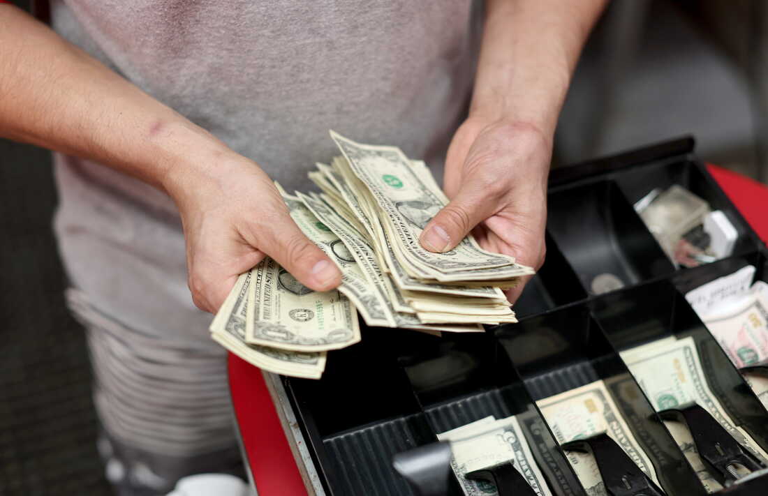 A cashier sorts money at a pizza shop in Miami.