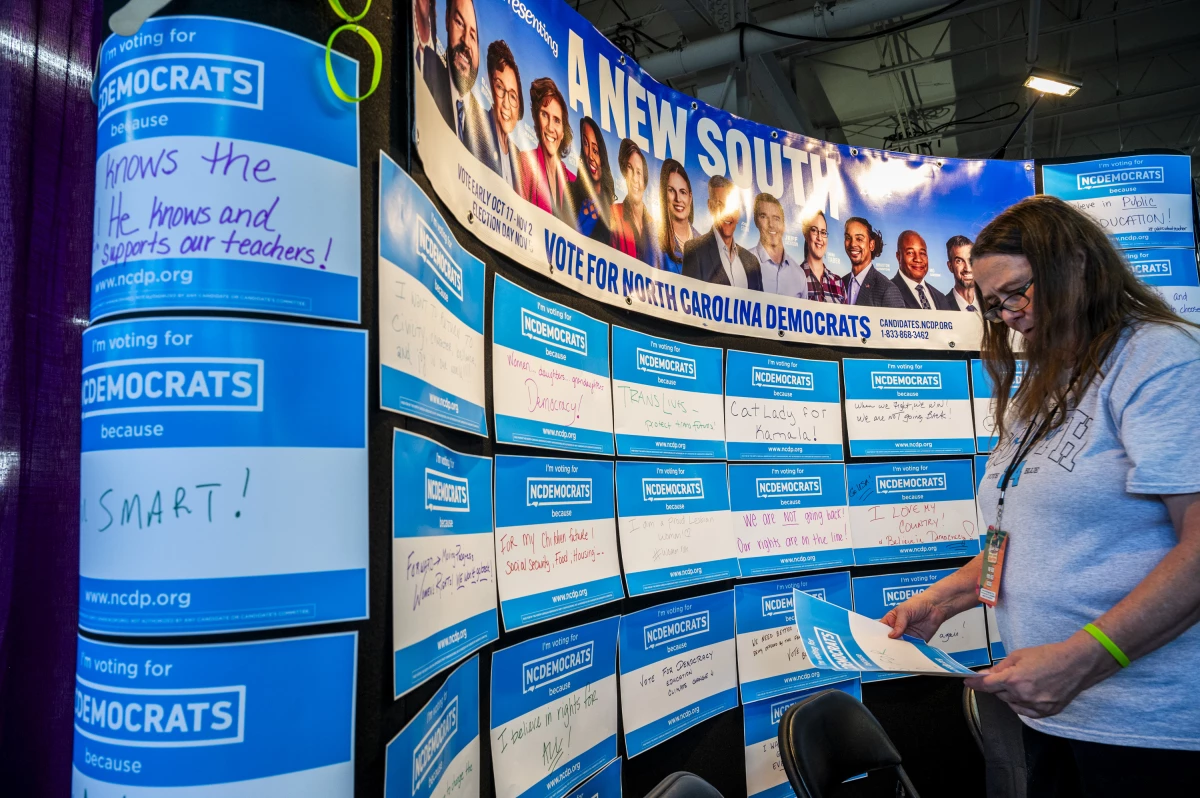 A volunteer for the Democratic Party puts up signs filled out by fairgoers about why they are voting.
