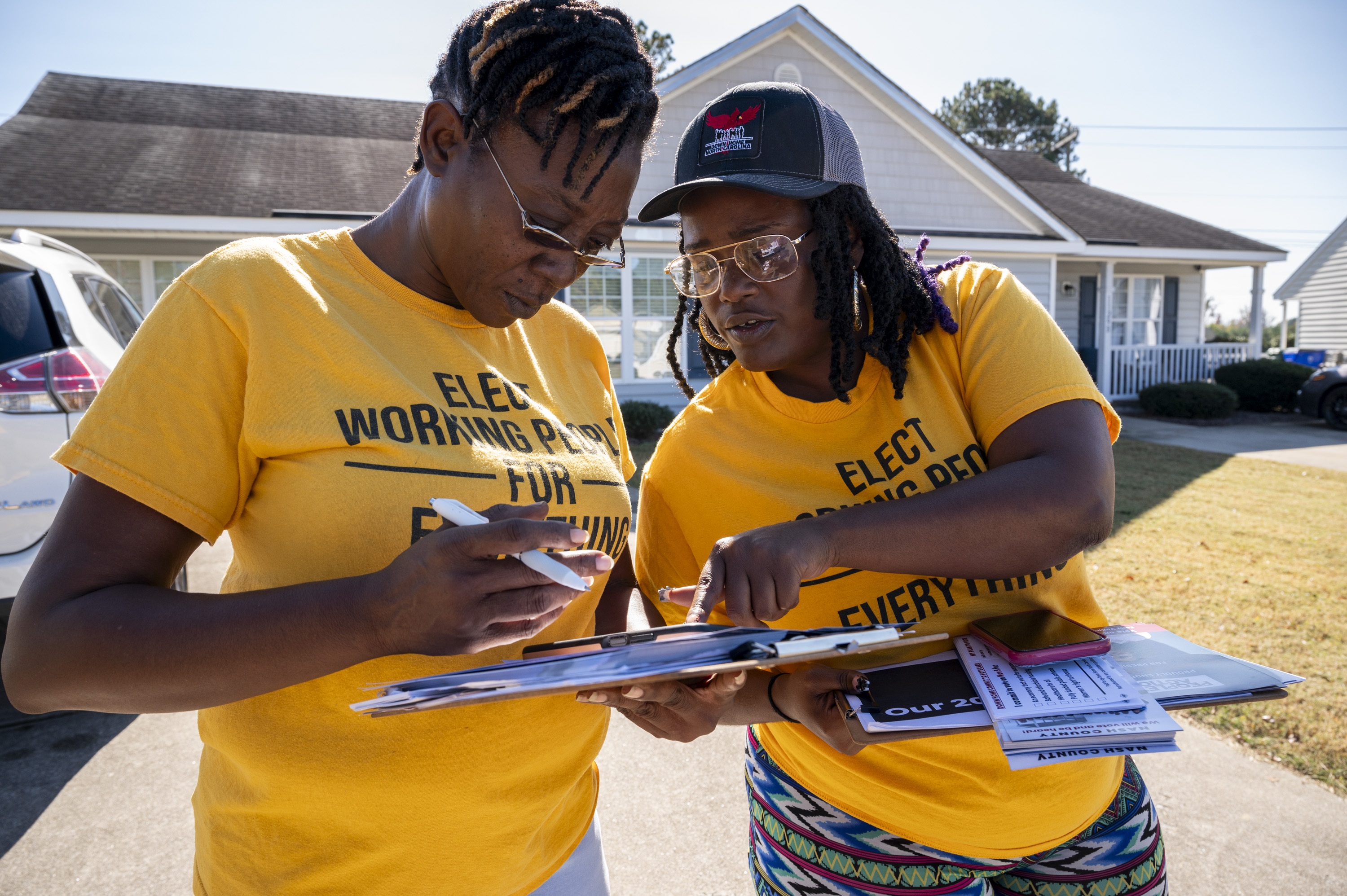 Andrea Farmer (left) and Alex Cook mark off homes they have visited on their app while canvassing in a neighborhood in Nashville, North Carolina in October.