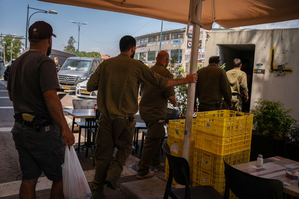 Soldiers and civilians enter a rocket shelter as sirens sound in the Israeli town of Kiryat Shmona on the Lebanese border on June 10.