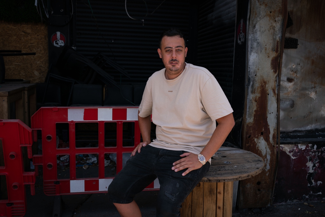 Asaf Maman, 31 sits in from of the burnt wreckage of Achim Mamam, a shawarma restaurant he owns that was hit by a Hizballah rocket early November 2023, in the Israeli town of Kiryat Shmona on the Lebanon border on June 10. He was working inside the restaurant when the rocket hit and his 25 year old brother took a stomach wound from shrapnel that he is still recovering from.