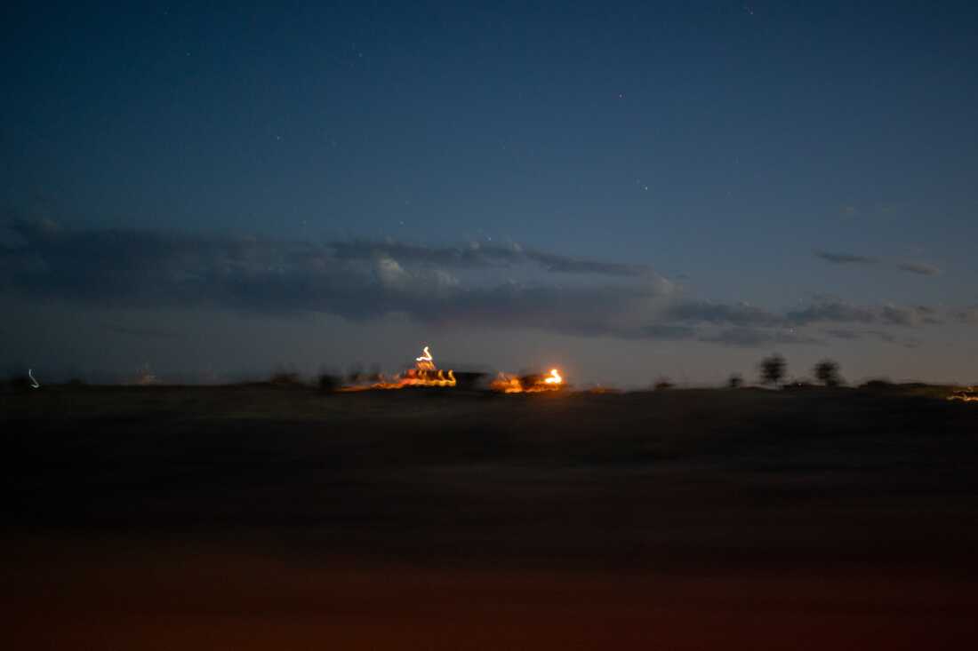 A few distant lights streak across a night sky in this long-exposure photograph.