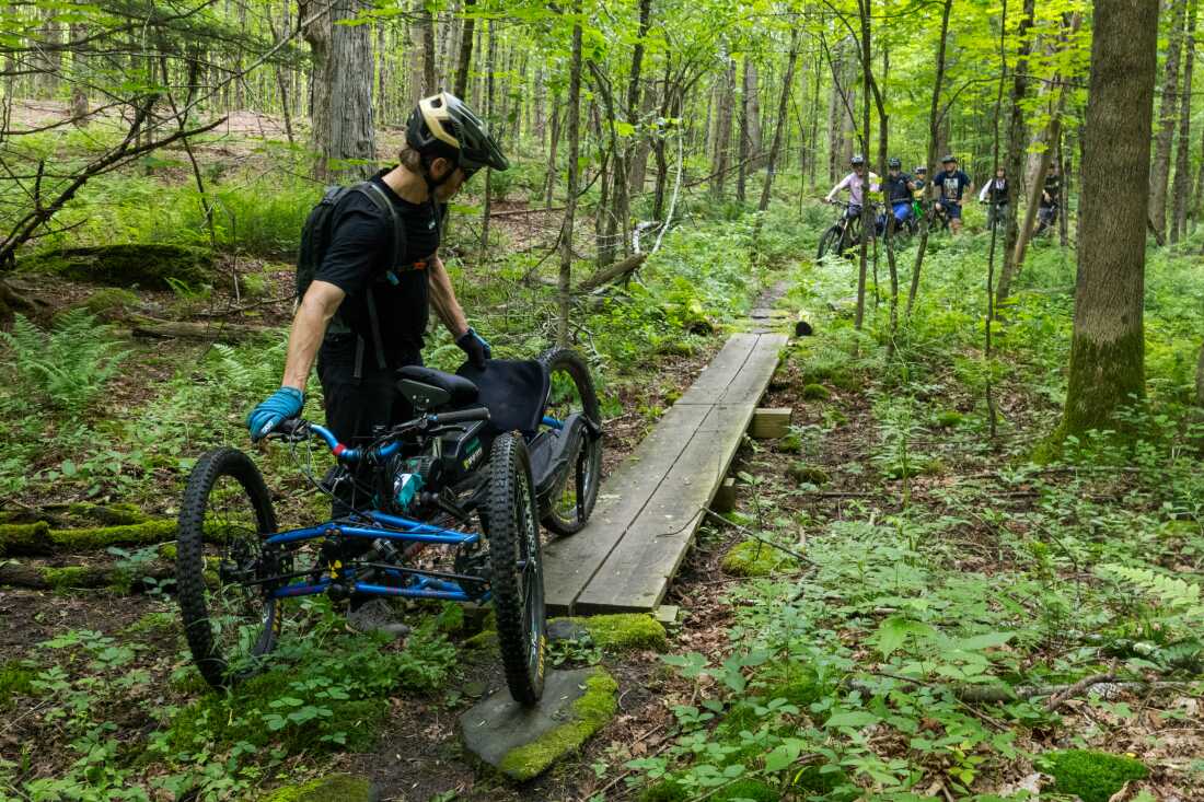 Nick Bennette, of the Vermont Mountain Biking Association, guides an adaptive bike over a narrow bridge, pointing out that other adaptive riders may have trouble getting across.