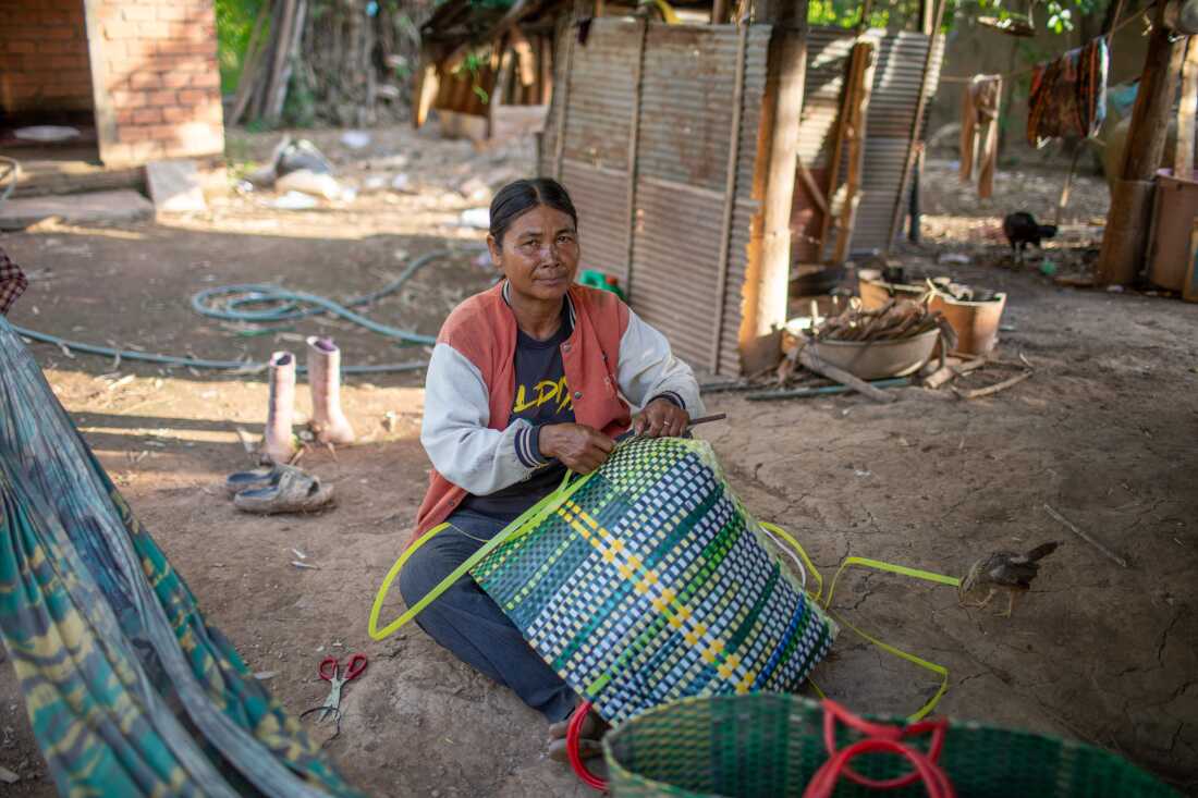 Forty-six-year-old Chhum Chhin weaves a basket in the shade of her home, which is on stilts.