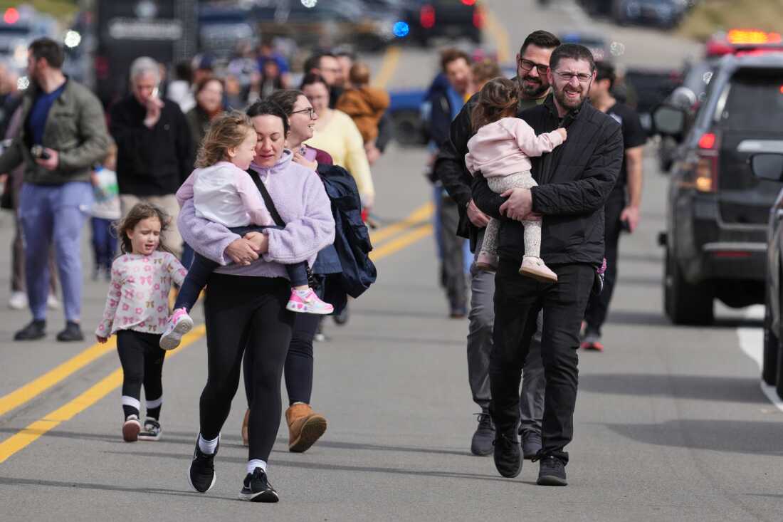 Law enforcement officers escort families with children away from the Temple Israel synagogue on March 12, 2026, after a shooting and vehicle ramming attack by a person inspired by Hezbollah.