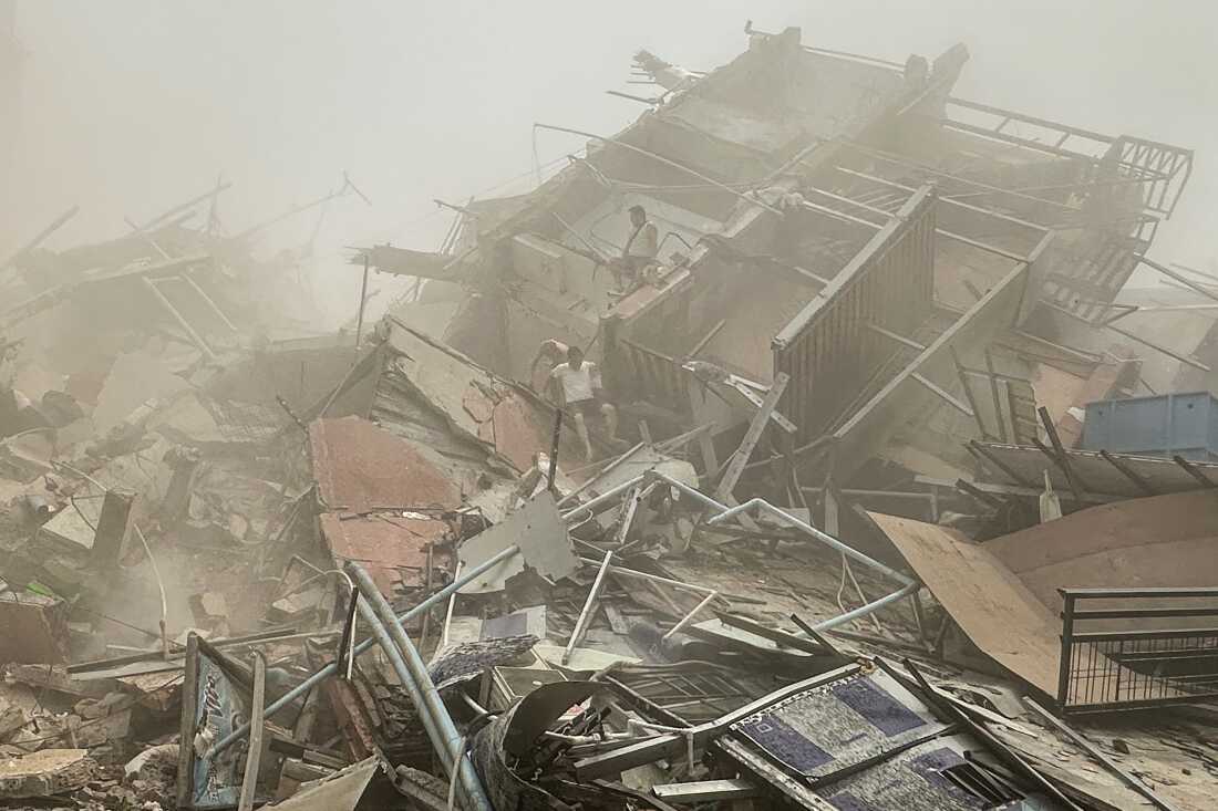 People inspect the debris of a collapsed building