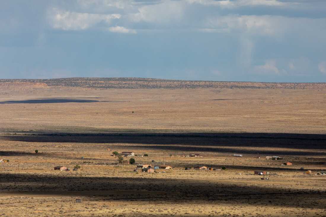 Dark shadows cross a dry yellow landscape dotted with buildings and homes.