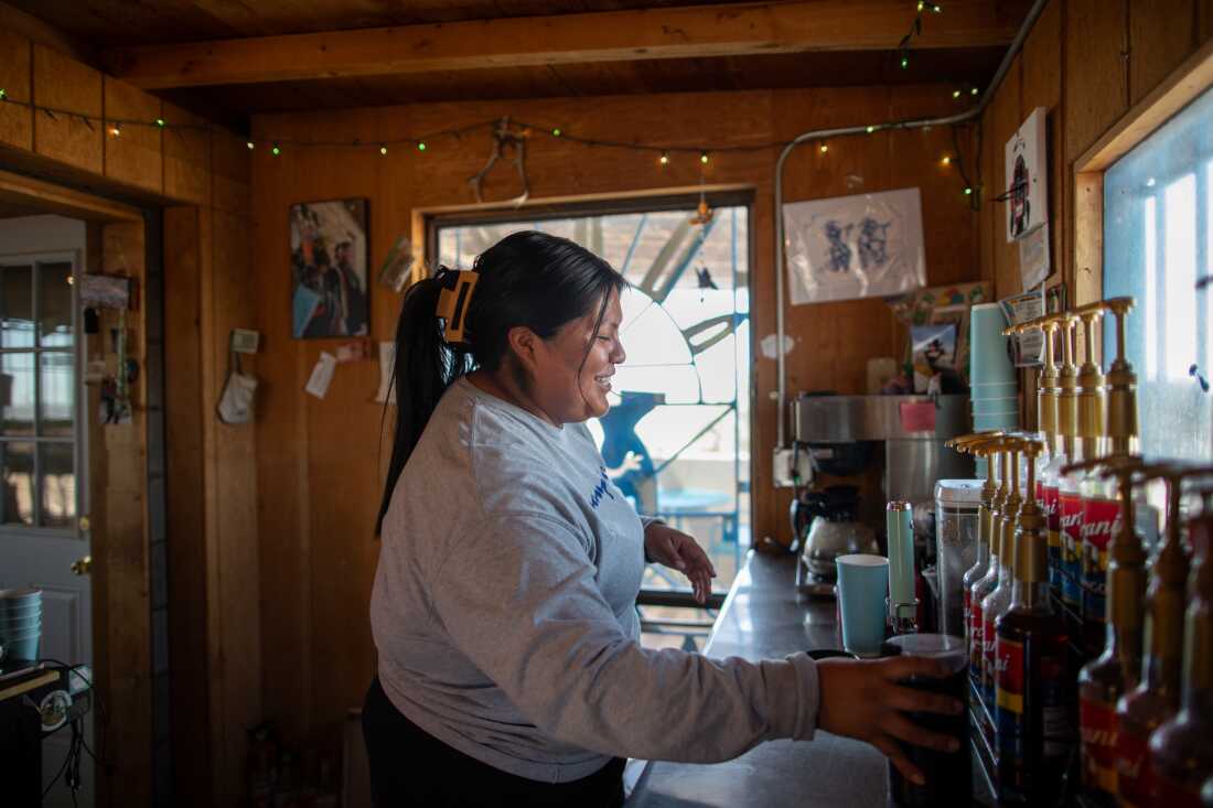 Storm Tso mixes up a drink at Hopi Grounds. Standing at a countertop, she's holding a cup near some bottles of flavored syrup.