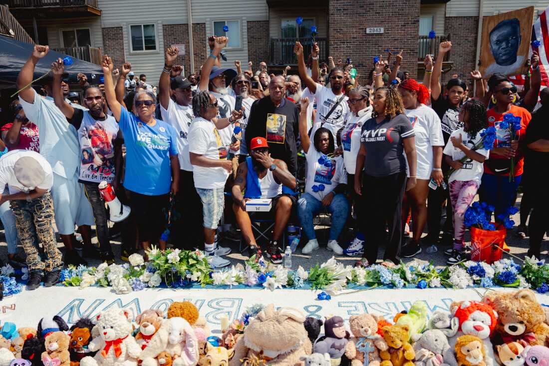 Community activists raise their fists as Michael Brown Sr., center in St. Louis Cardinals hat, wipes his face on Friday, Aug. 9, 2024, during a Canfield Drive memorial service commemorating a decade after Brown Jr.’s police killing in Ferguson.