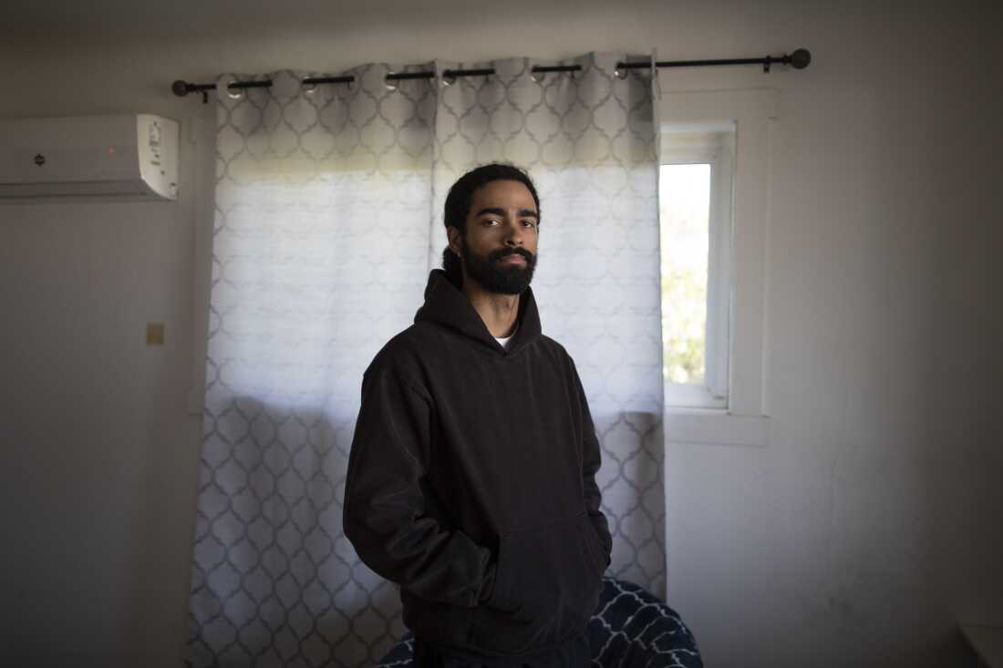 Mason Swinnie stands in front of a window that's covered by a curtain. 