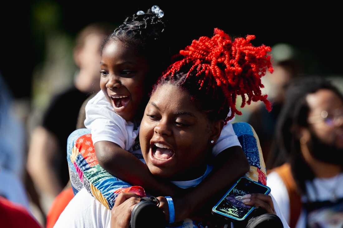 Trinaya’ Walker, 22, holds her daughter Bobbie Ann Atkins, 6, on Friday, Aug. 9, 2024, during a unity march commemorating a decade after Michael Brown Jr.’s police killing in Ferguson. Walker said she is Brown Jr.’s sister.