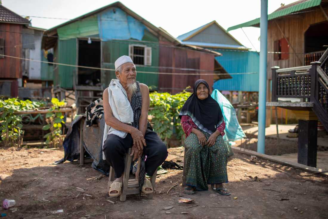 Ker Sman, 82 and his wife, Chhres Yas, 65, sit outside their home in the Cambodian village of Prek Touch.