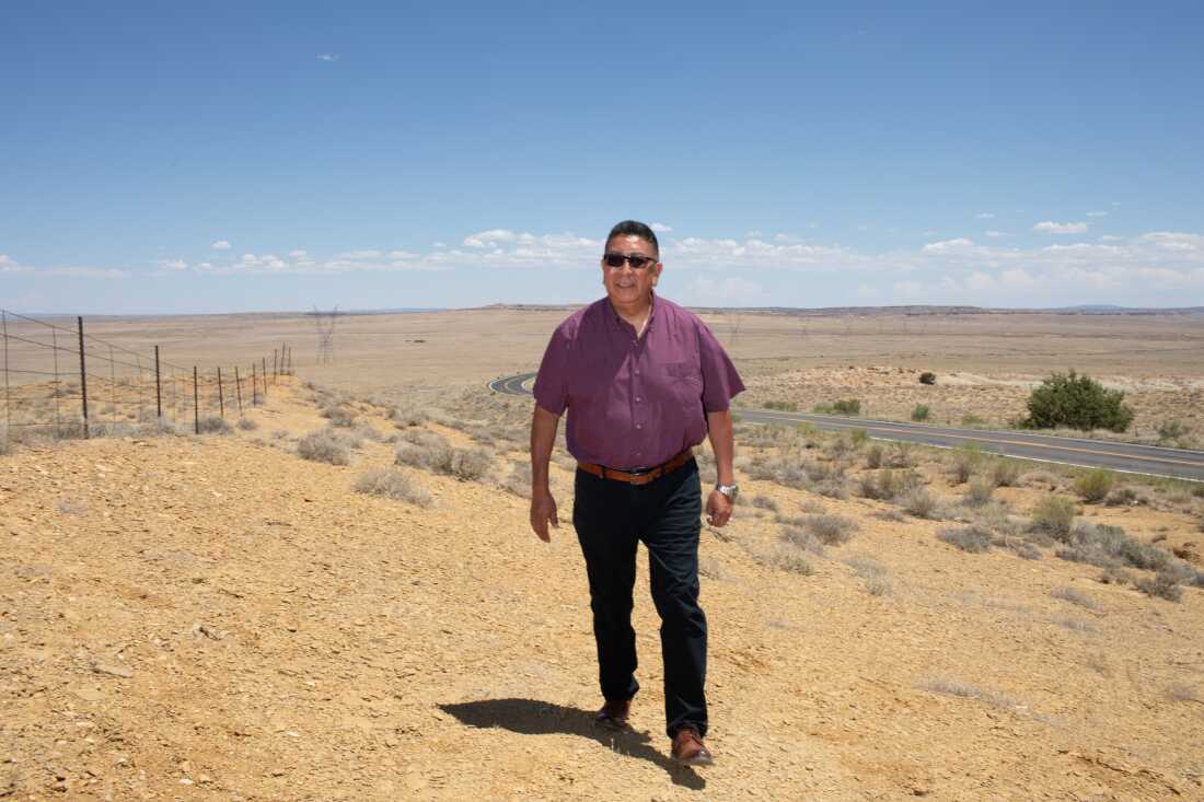 Hopi Chairman Tim Nuvangyaoma walks through a bright desert landscape toward the camera.