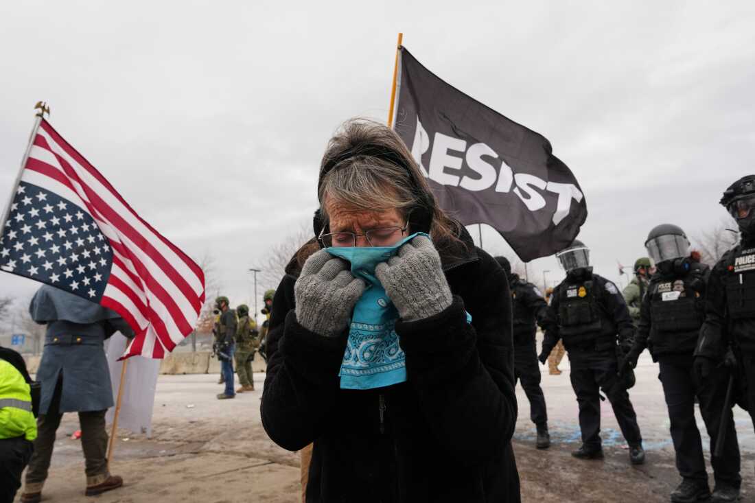 A woman covers her face from tear gas as federal immigration officers confront protesters outside Bishop Henry Whipple Federal Building, Jan. 15, 2026, in Minneapolis.