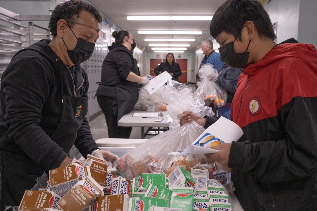 Jose Centeno hands food to LAUSD student Jesus Sanchez at Hollenbeck Middle School on Friday, Jan. 10.