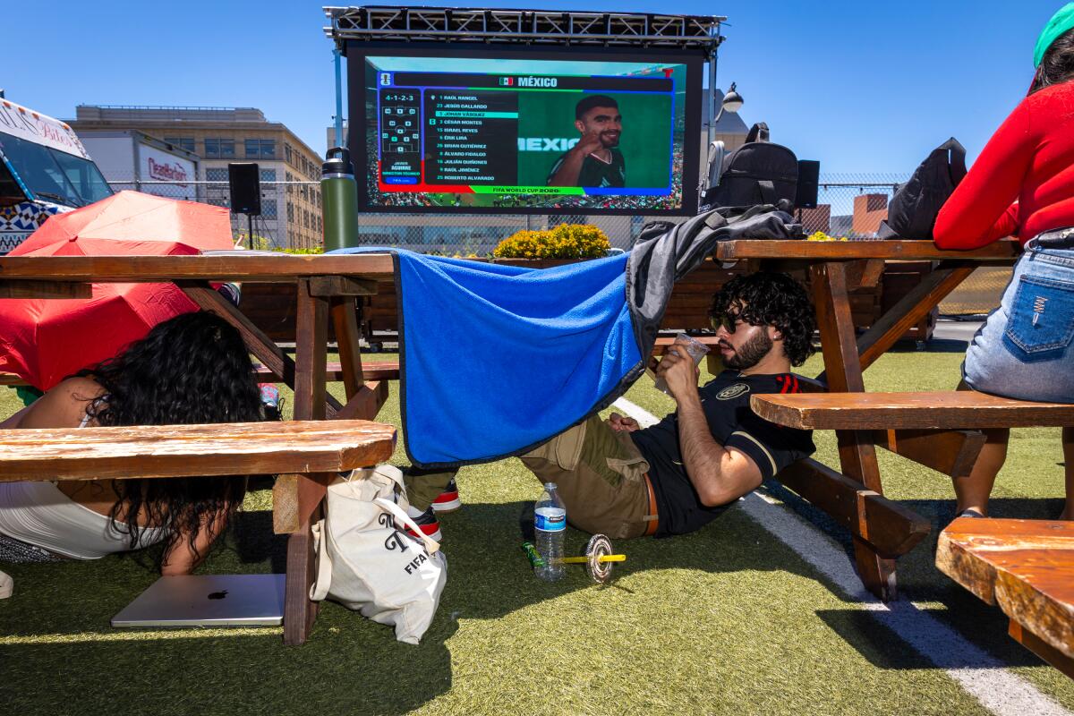 People find shade under tables, benches and blankets at a Mexico vs. South Africa World Cup watch party at SPARK Social SF in San Francisco on Thursday, June 11.