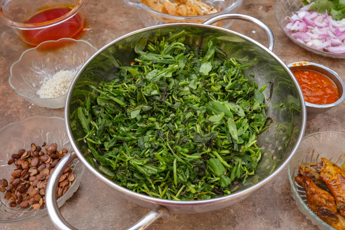 A spread of fresh ingredients used in waterleaf soup include waterleaf (gbure), crayfish, chicken, cowskin, stockfish, turkey, palm oil, locust beans, onions and salt.