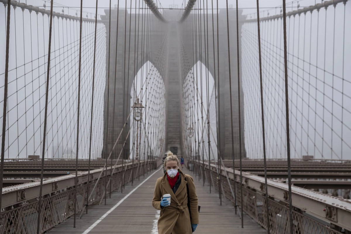 March 20, 2020: A woman wears a mask walking over the Brooklyn Bridge as a COVID-19 outbreak rocks New York City.