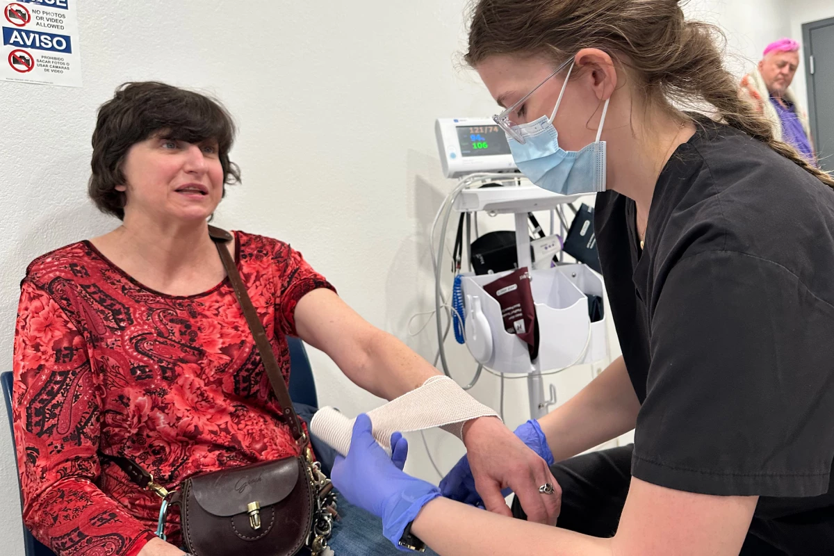 On-site emergency medical technician Emily Woolsey wraps the swollen wrist of MVP shelter resident Jamie Mangum after a fall. Mangum says that in other shelters, she would likely have had to find her own way to an urgent care office to get treatment. She credits the shelter for helping her deal with all her medical issues.