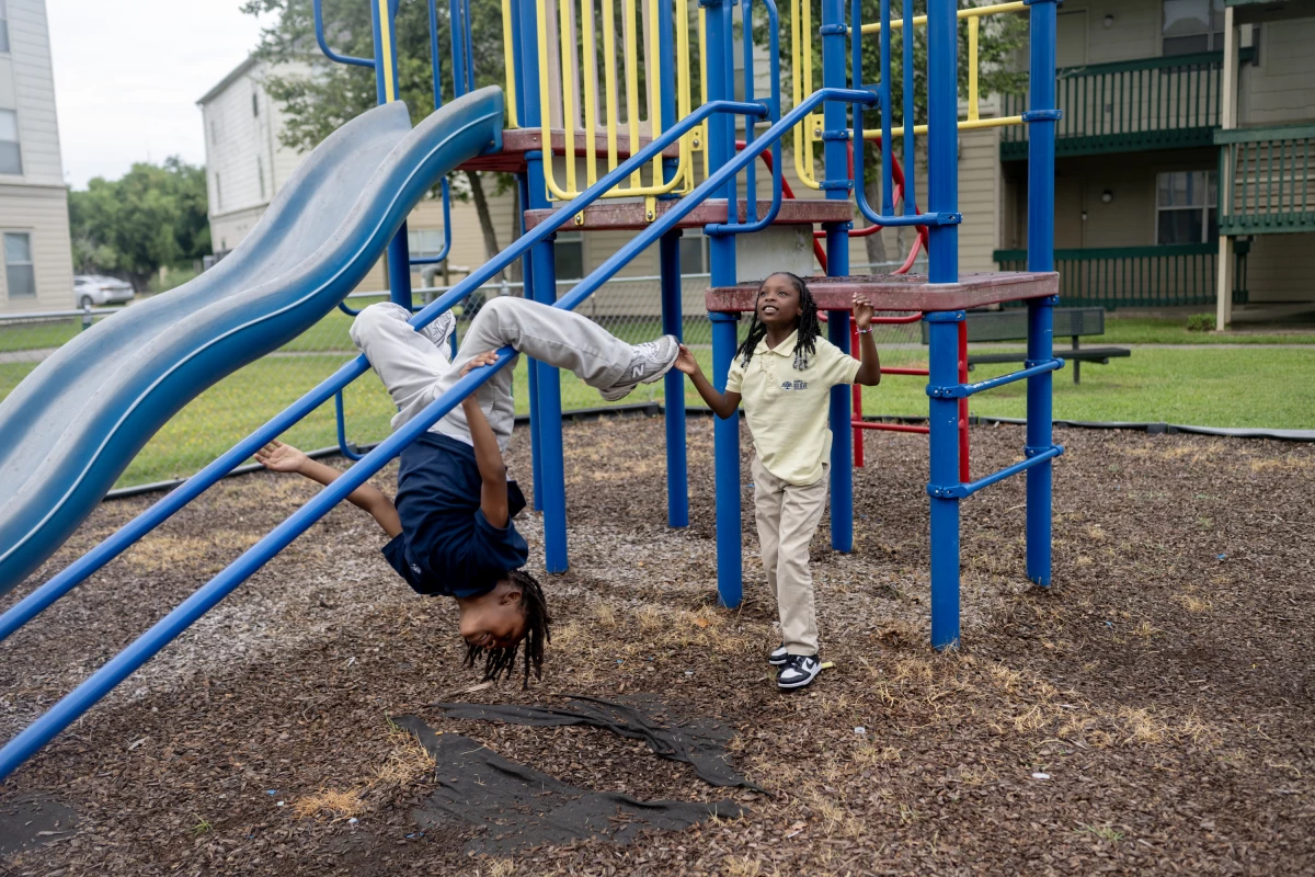 Brother and sister Harlem and Harmony play on a playground outside their apartment complex in New Orleans. Both children attend a KIPP school, like their mom did.