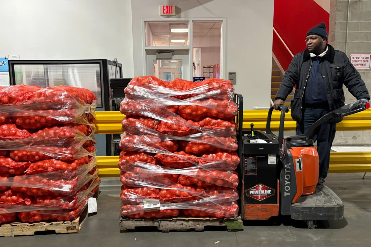 At the Greater Boston Food Bank, warehouse lead Adrian James drives a palette of onions destined for one of the area food pantries. He fears the recent spike in demand is 'just the beginning.'