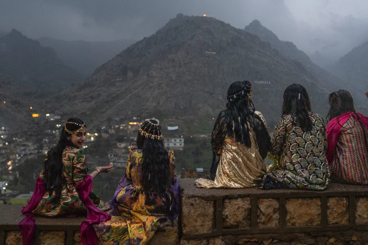 Girls sit on a wall to get a good vantage point of people walking up the mountains with flaming torches and fireworks for Nowruz in Akre, the Kurdish region of Iraq on Friday.