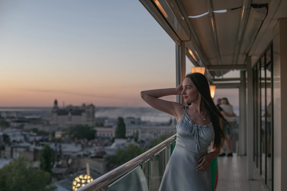 A girl poses for a photo in a restaurant overlooking Odesa on Aug. 14, where smoke from a shelling that occurred just moments earlier can be seen in the background.