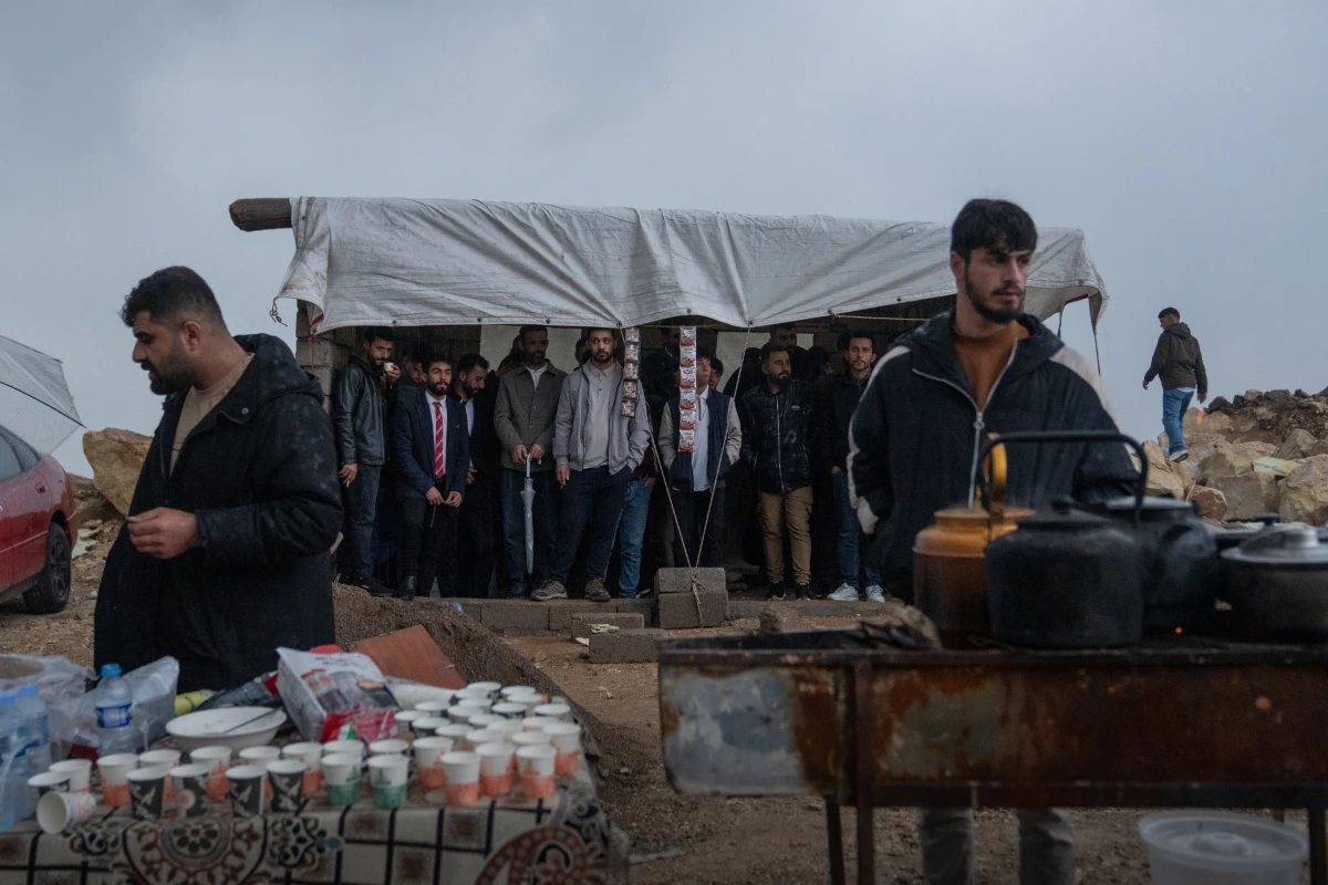 People stand under a tent on a hilltop to avoid the pouring rain while waiting for the Nowruz festivities.