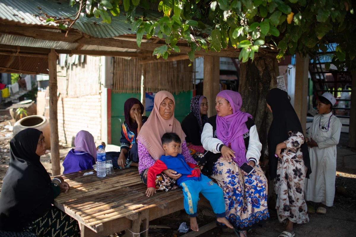 Fish sellers Kly Phally (left), Sen Srod and Karey Sa Vai (right) sit outside their homes in the Cambodian village of Prek Touch. Water was 10 feet high in this area during a flood in November 2025.