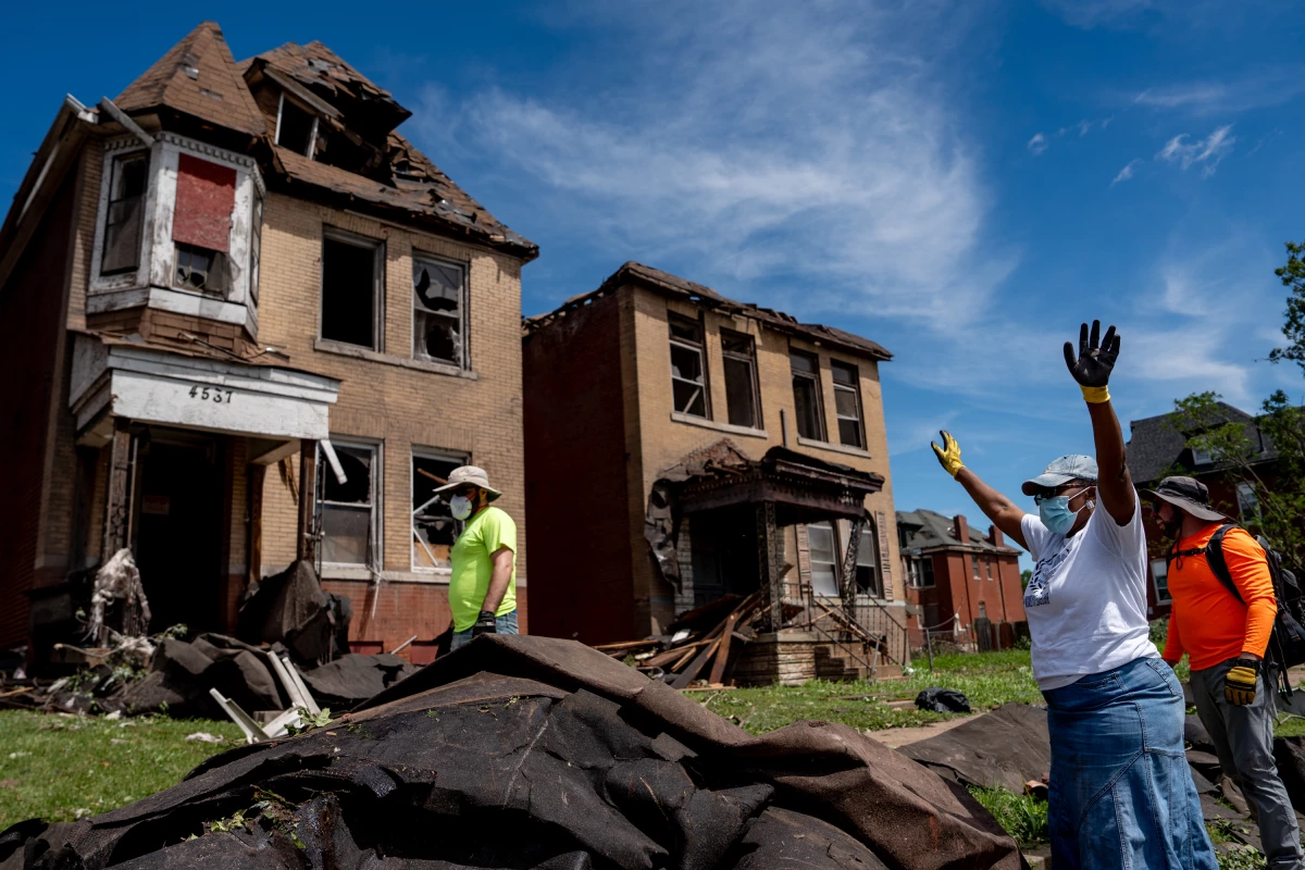 Debra El (right) rejoices after volunteers are able to get roof lining off of the road in north St. Louis on Saturday.
