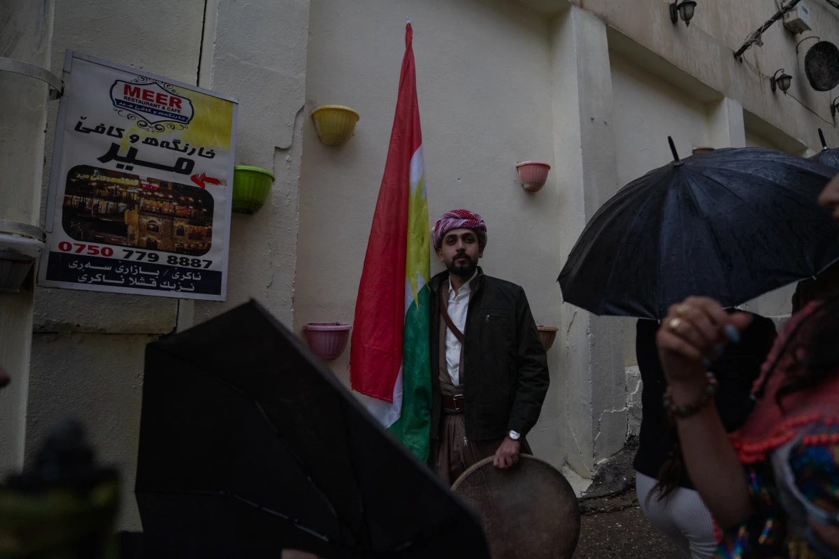 Ismail Mohammad, 28, holds a Kurdish flag and a drum as people pass by at the Nowruz festivities.