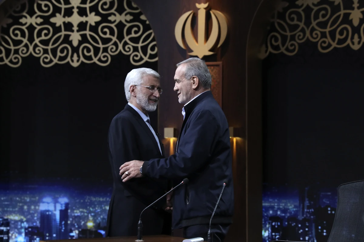 In this photo made available by Iranian state-run TV, IRIB, Iranian presidential candidate Saeed Jalili, left, a hard-line former nuclear negotiator, and reformist candidate Masoud Pezeshkian greet one another at the conclusion of a debate at the TV studio in Tehran, Iran, on June 1, 2024.