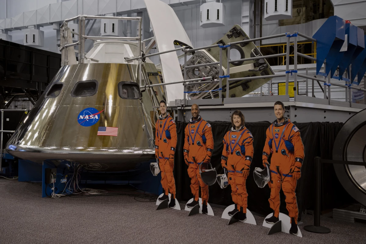 Cardboard cutouts of the Artemis II crew next to the Orion spacecraft mockup.