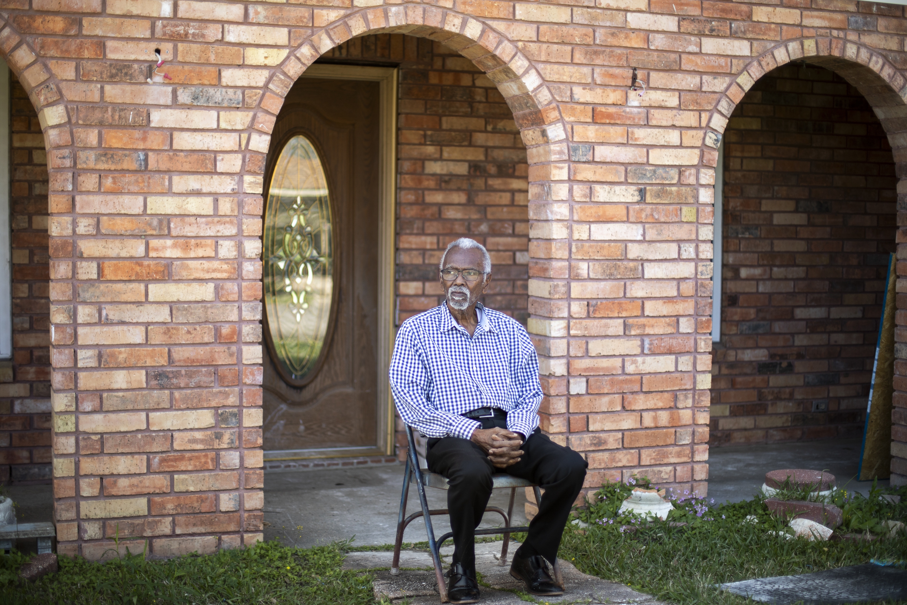 Robert Taylor sits outside the two-story brick home he built in Reserve, Louisiana. It's within walking distance to the Denka Performance Elastomer plant, which announced on May 13 it would suspend production indefinitely. Taylor and some of his neighbors have lived in close proximity to the plant for over 50 years. (NPR)