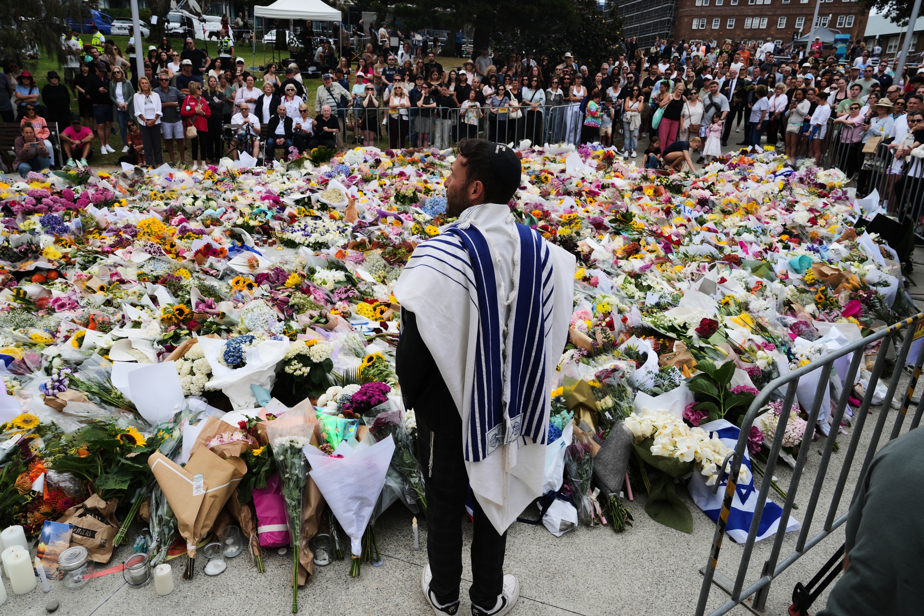 Rabbi Yossi Friedman speaks to people gathering at a flower memorial by the Bondi Pavilion at Bondi Beach on Tuesday, following Sunday