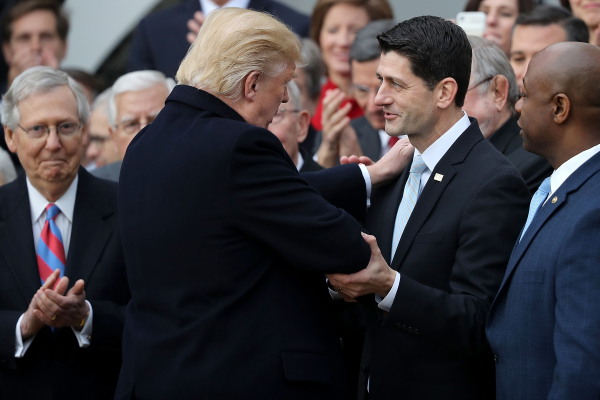Donald Trump places a hand on Paul Ryan's shoulder as the two men face each other and Ryan grips Trump's elbow.