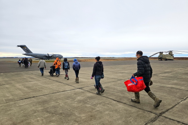 Evacuees head to board a C-17 military cargo plane on the first day of mass evacuations from Bethel to Anchorage on Oct. 15, 2025.