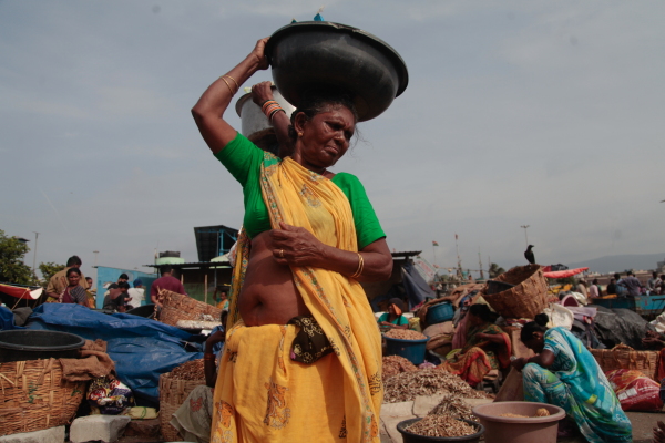 Fishwives sell mounds of dried fish and shrimp at the port of Visakhapatnam, where much of the economy is based around seafood exports — chiefly frozen shrimp to the U.S. India’s shrimp is a $5 billion dollar export market — much of it cleaned, frozen and packed and exported to the U.S. - where it once formed two out of every five pounds for shrimp in America. But after President Trump imposed 25% tariffs on India, and then doubled it, Indian shrimp industry businesses say they’ve been priced out of the market. The industry had long been under scrutiny for its exploitative labor conditions, its environmental impacts, and for human rights abuses related to the industry, like land theft. Image by Diaa Hadid, Visakhapatnam, Andhra Pradesh, India, August 2025.