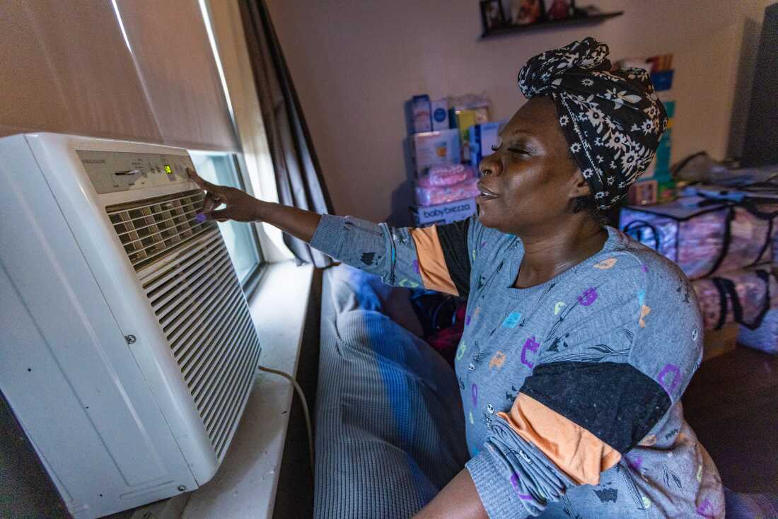 Kiki Polk, one of the first Boston Medical Center patients to enroll in the Clean Power Prescription program, turns on the air conditioner in her home in Boston.