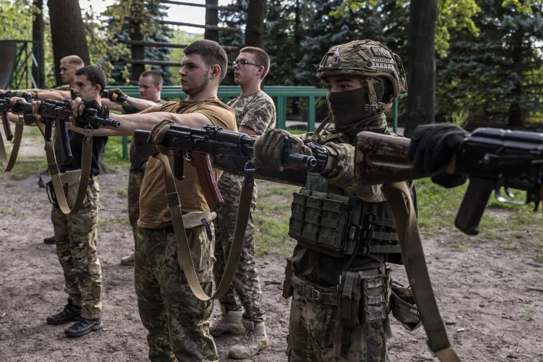 Ukrainian participants do an exercise holding a rifle as long as possible with straight arms in the military's 