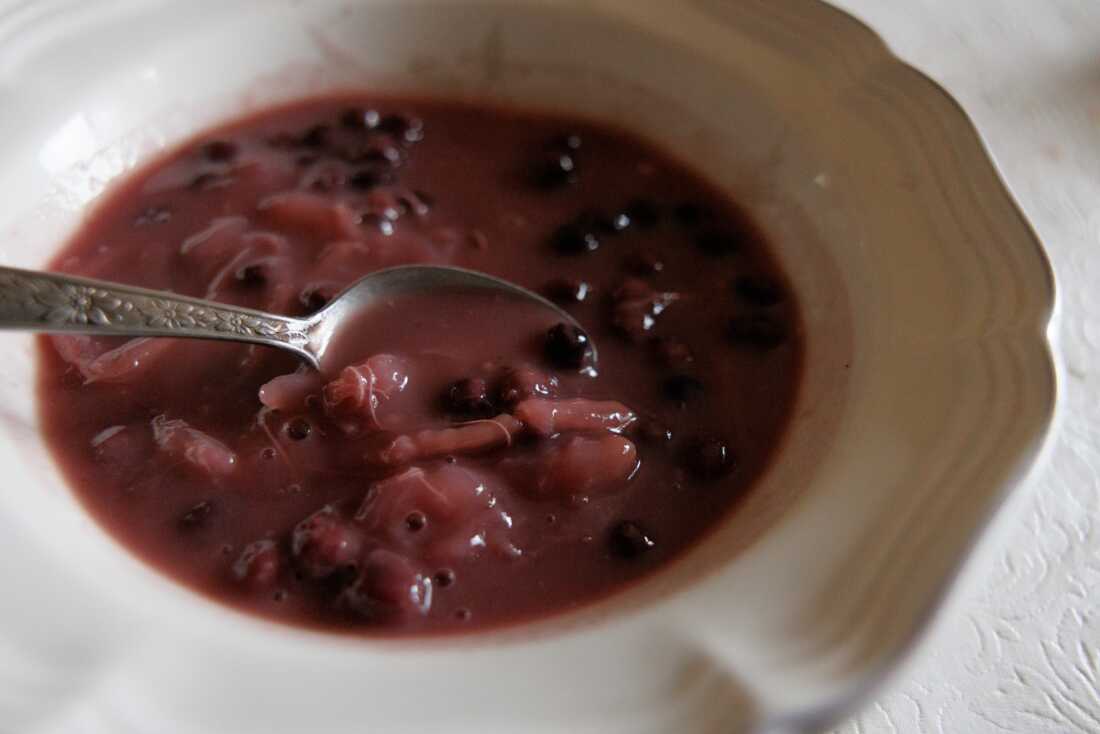 A bowl of berry soup with a spoon in the soup.