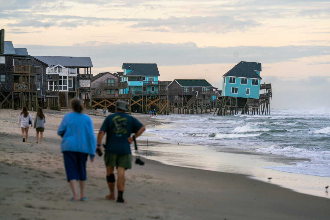 Houses perched on wooden stilts stand along the Cape Hatteras National Seashore in May. One house is tilted precariously toward the ocean.