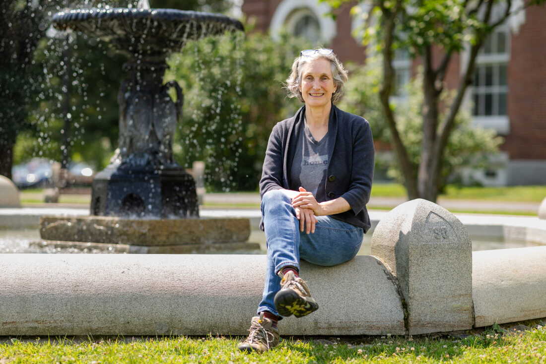 Rebecca Holcombe, a co-founder of the Greenway Institute, sits on a border surrounding a fountain.