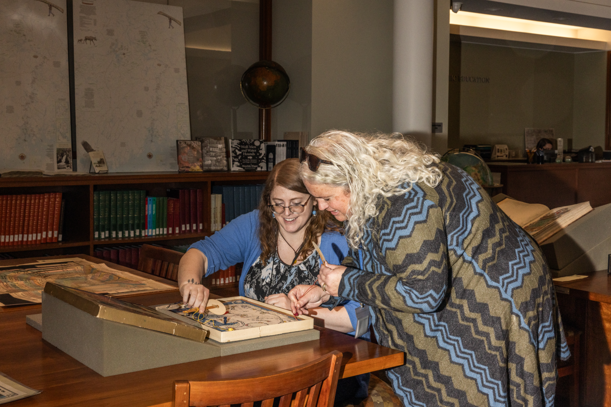 Renee Keul, Assistant Director for Education and Outreach, and Dr. Libby Bischof, Executive Director, demonstrate a cartographic game. The maps in the collection are allowed to be touched and interacted with.