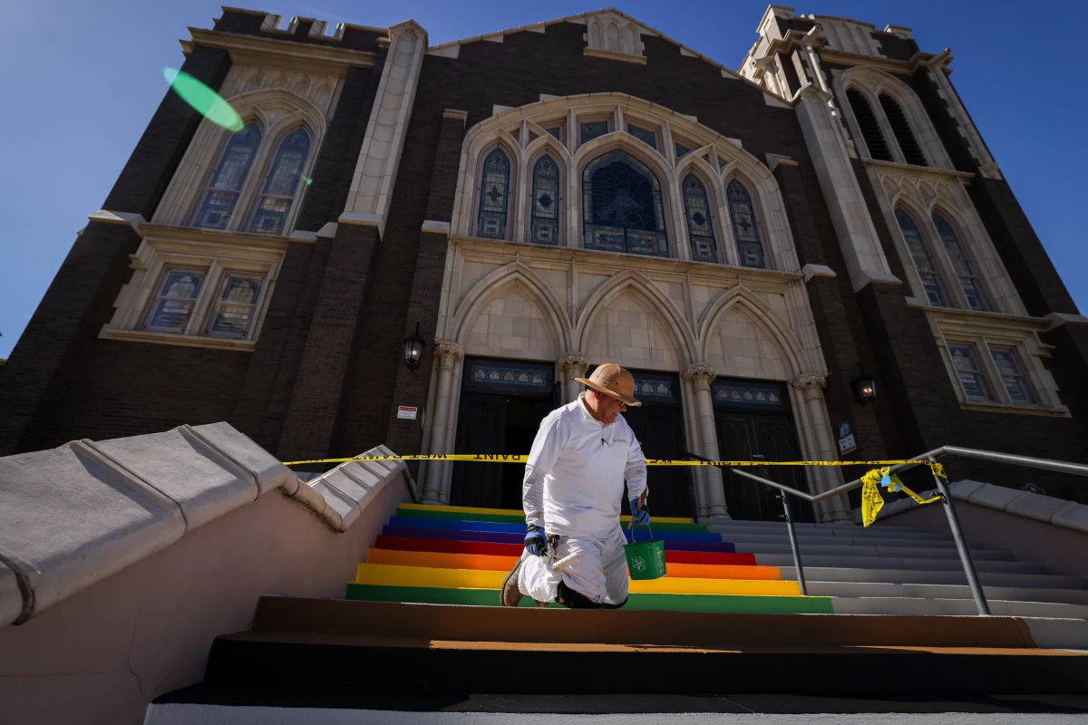Robert Garcia paints the stairs of Oak Lawn United Methodist Church in Pride and trans colors Wednesday, Oct. 22, 2025, in Dallas, Texas. The church made the move in response to Texas Gov. Greg Abbott's order to remove symbols from crosswalks in cities across the state.