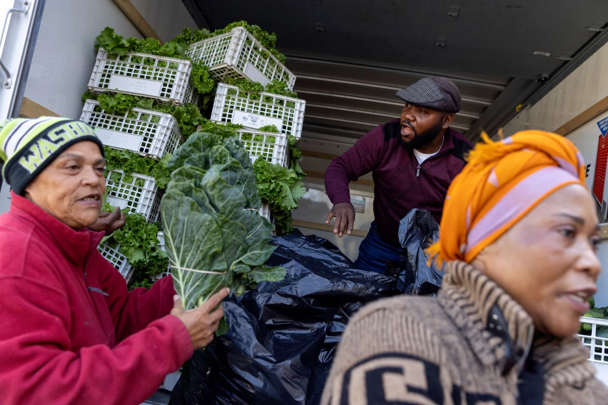 Agnes Mwamba (right) and her husband, Joseph (middle), of Agnes Farm and Produce in Brandywine, Md., offload 2,000 pounds of fresh vegetables that they brought to distribute to federal workers in Hyattsville, Md. Grace Herring (left) is a volunteer with No Limits Outreach Ministries, where the Oct. 28 distribution took place.